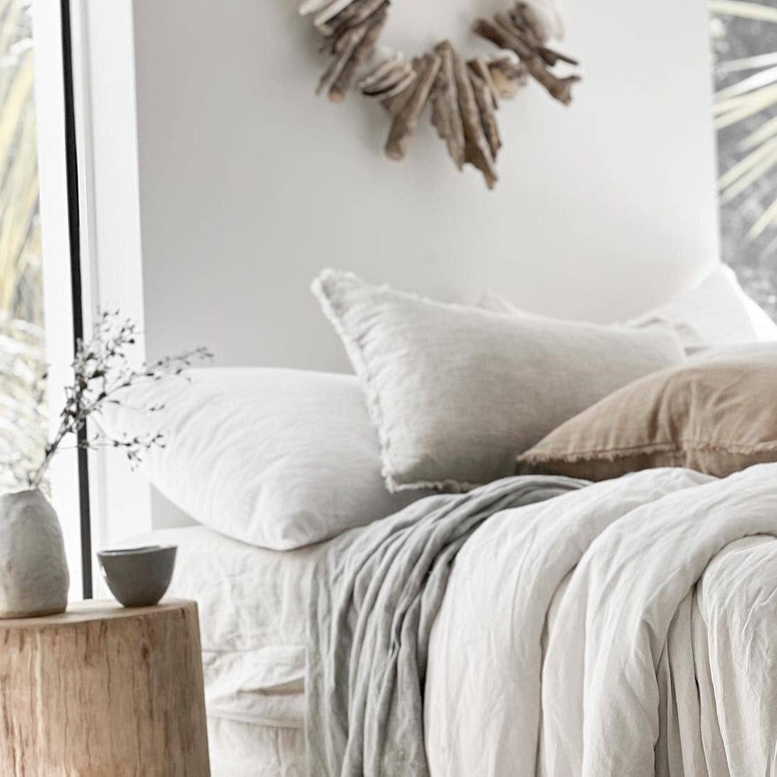 Neatly made bed with neutral bedding and pillows in a bedroom setting.