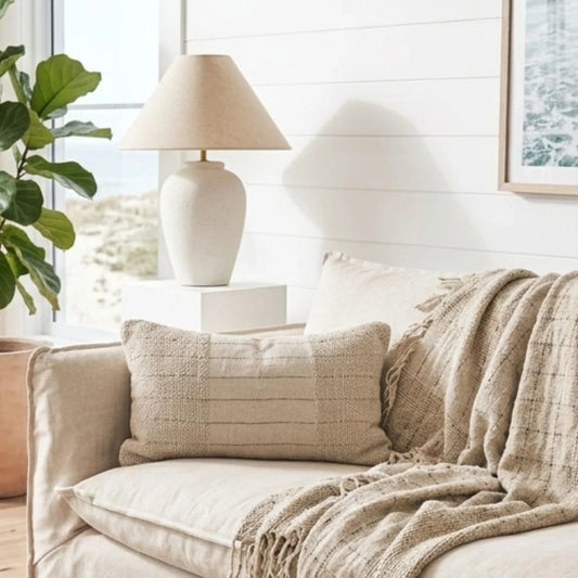 Cozy living room with a beige sofa, textured pillow, and lamp.