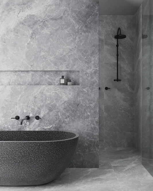 Modern bathroom with a freestanding bathtub against a marble wall.