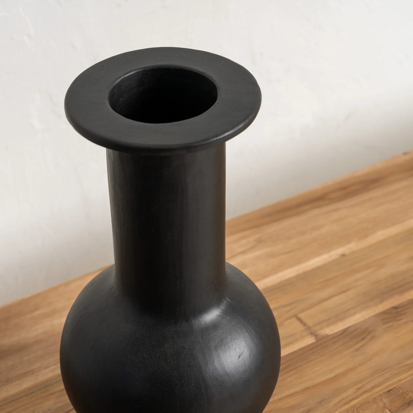 Black vase on a wooden surface with a white background