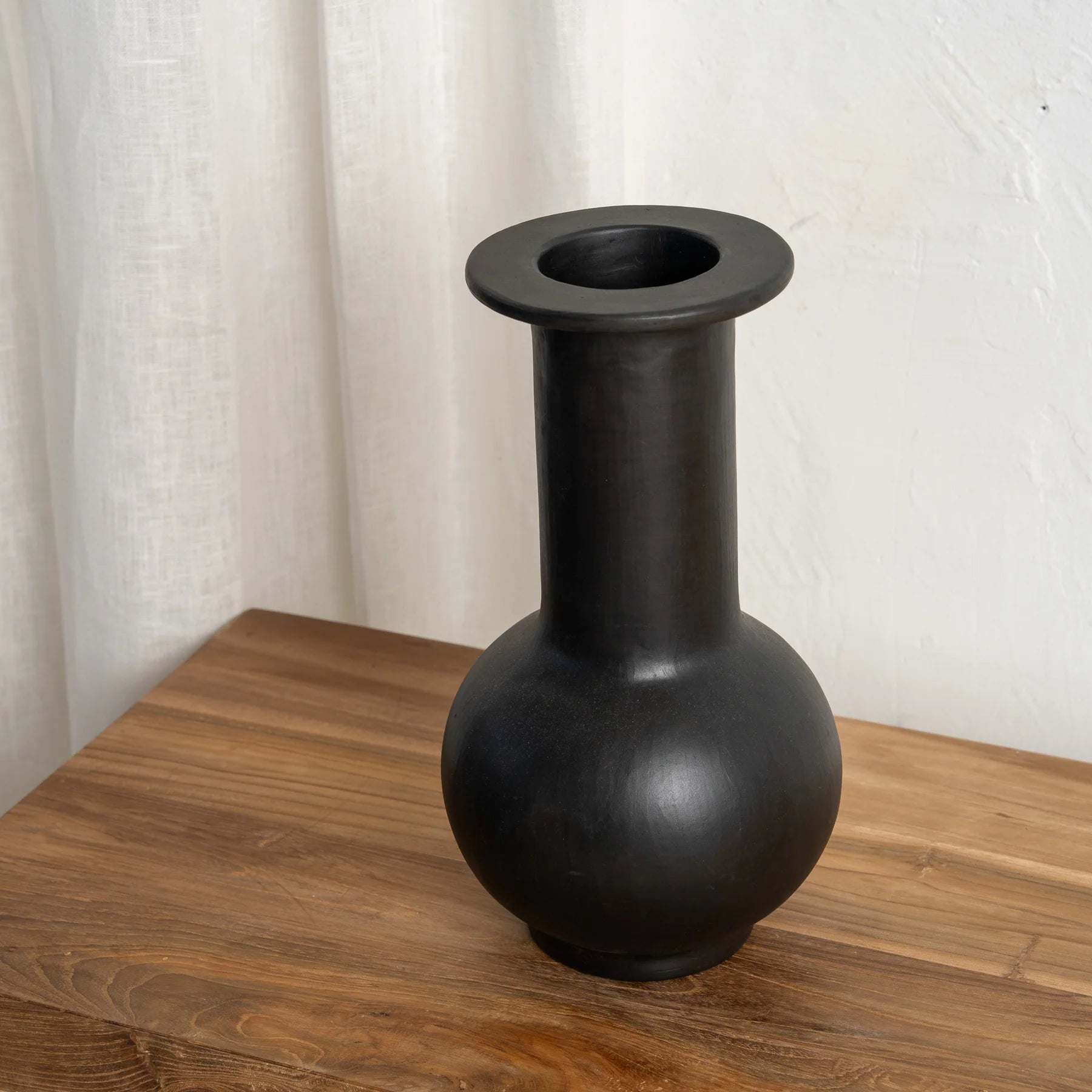Black vase on a wooden surface with a white background