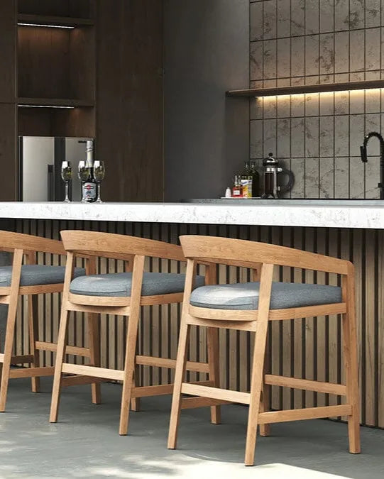 Wooden bar stools with gray cushions in a modern kitchen setting.
