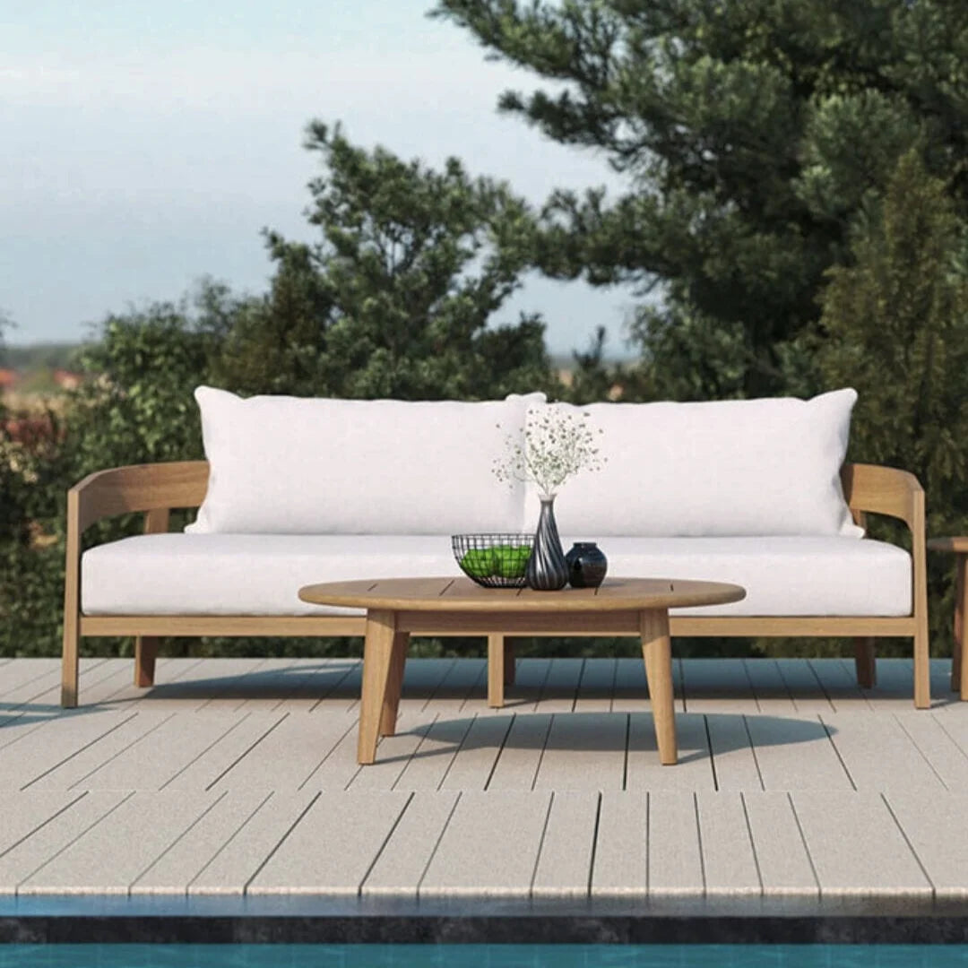 Outdoor furniture set with white cushions and a wooden table by a poolside.