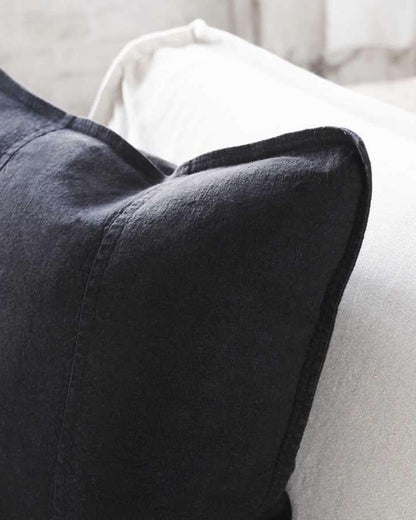 Close-up of a black pillow on a light-colored sofa.