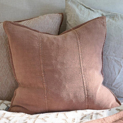 Clay coloured textured pillow on a bed with neutral bedding