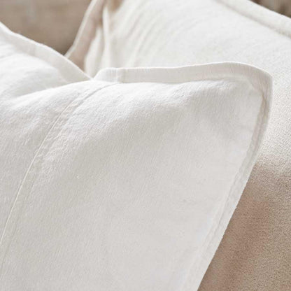 Close-up of a white fabric pillow on a beige background.
