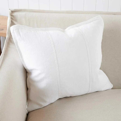 White pillow on a beige sofa in a simple indoor setting.