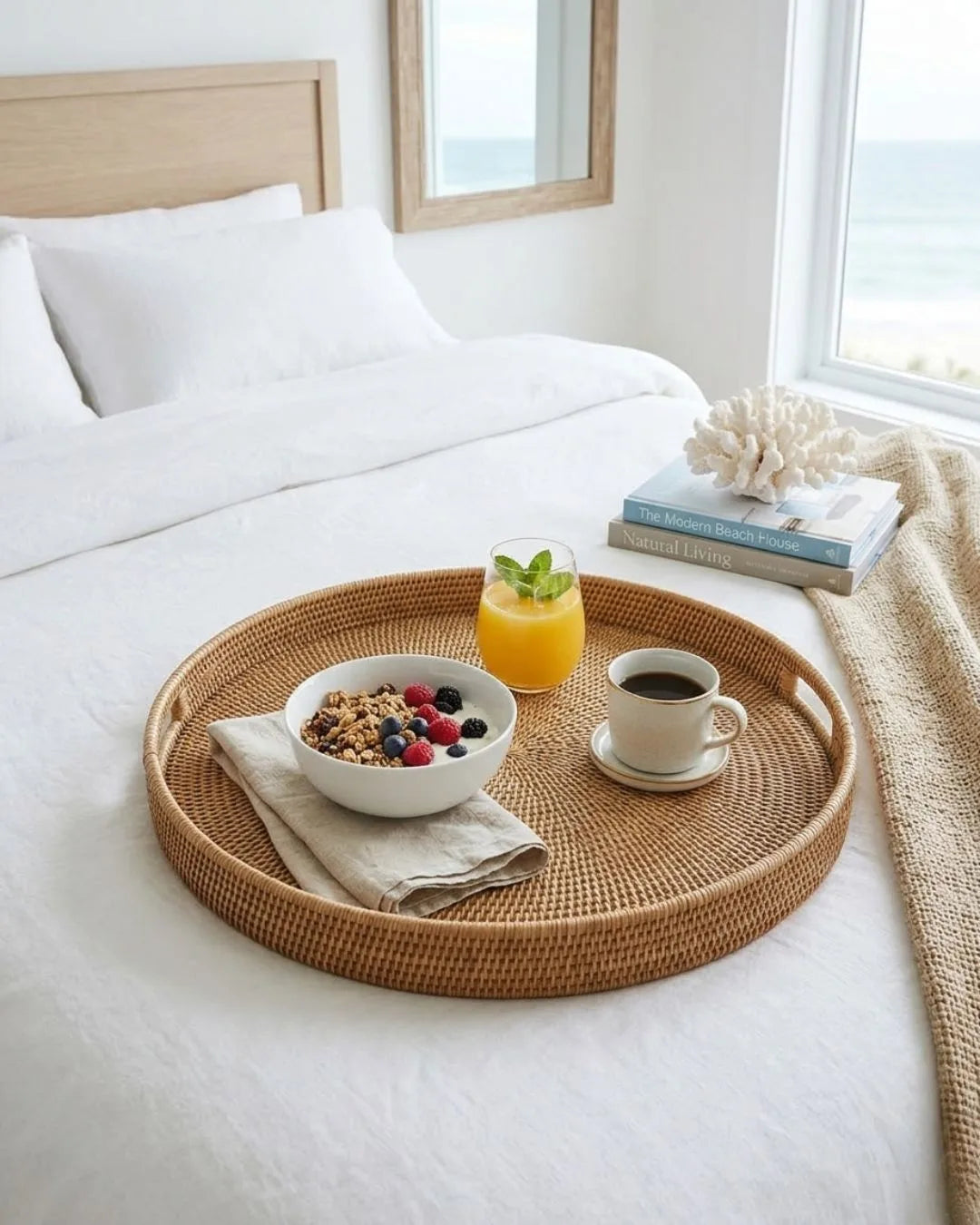Wicker tray with breakfast items on a bed in a bright room