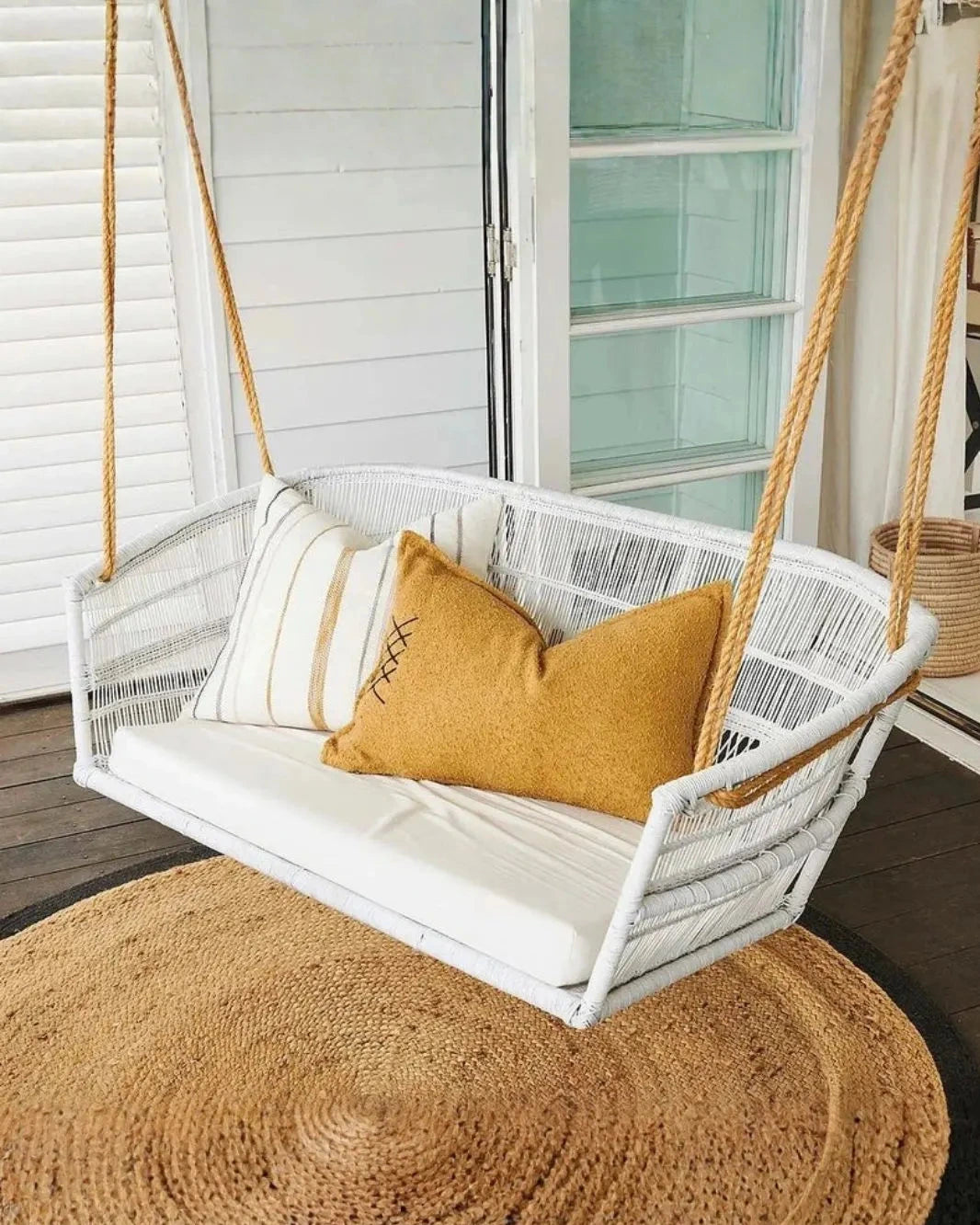 White hanging chair with cushions on a wooden floor