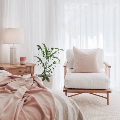 Cozy bedroom with a bed, chair, and lamp under sheer curtains.