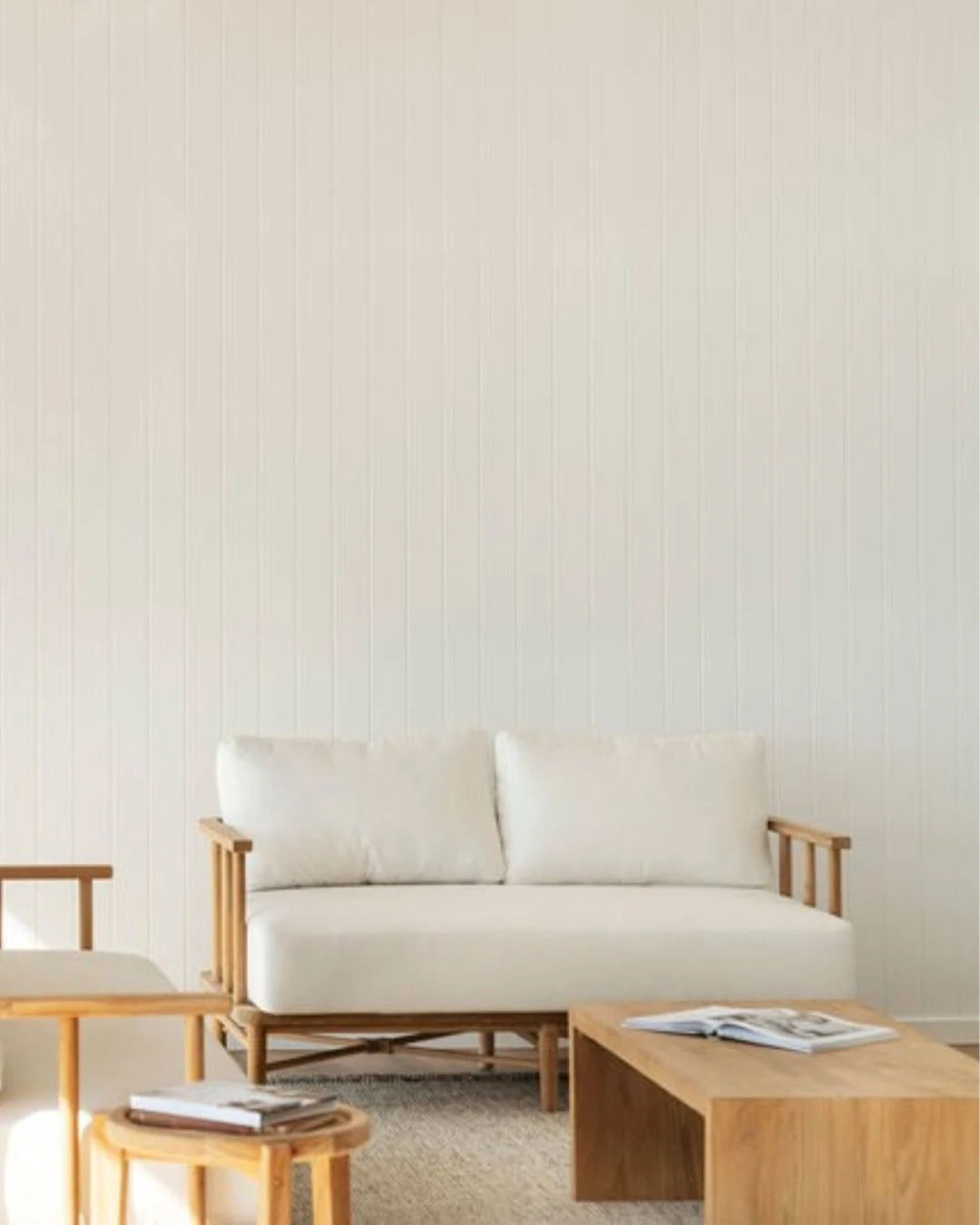 Teak outdoor sofa with white cushions in a outdoor living space with teak coffee table and side table.