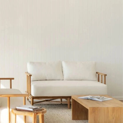 Teak outdoor sofa with white cushions in a outdoor living space with teak coffee table and side table.