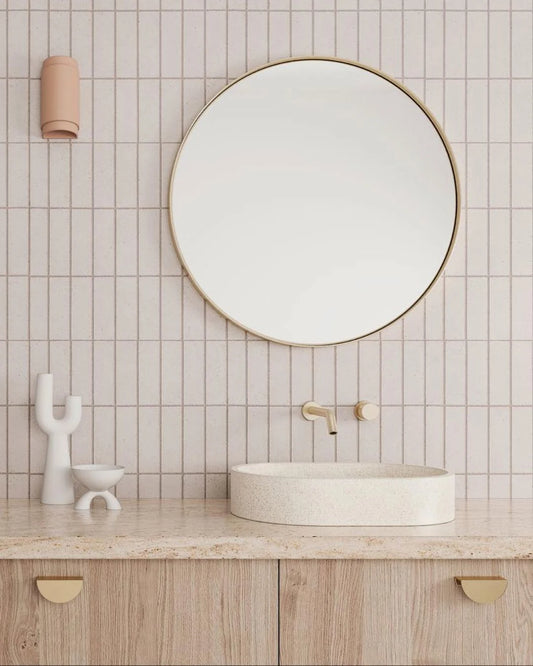 Bathroom with round mirror, sink, and tiled wall