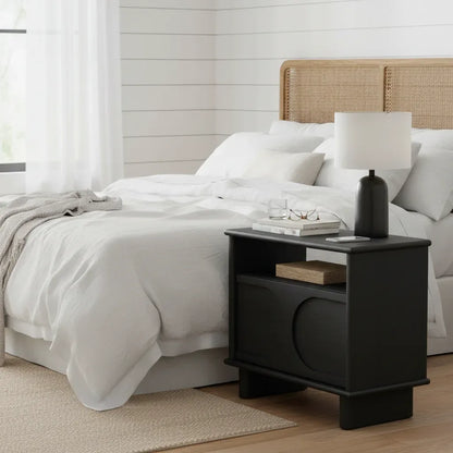 Bedroom with a bed and black nightstand featuring a lamp.