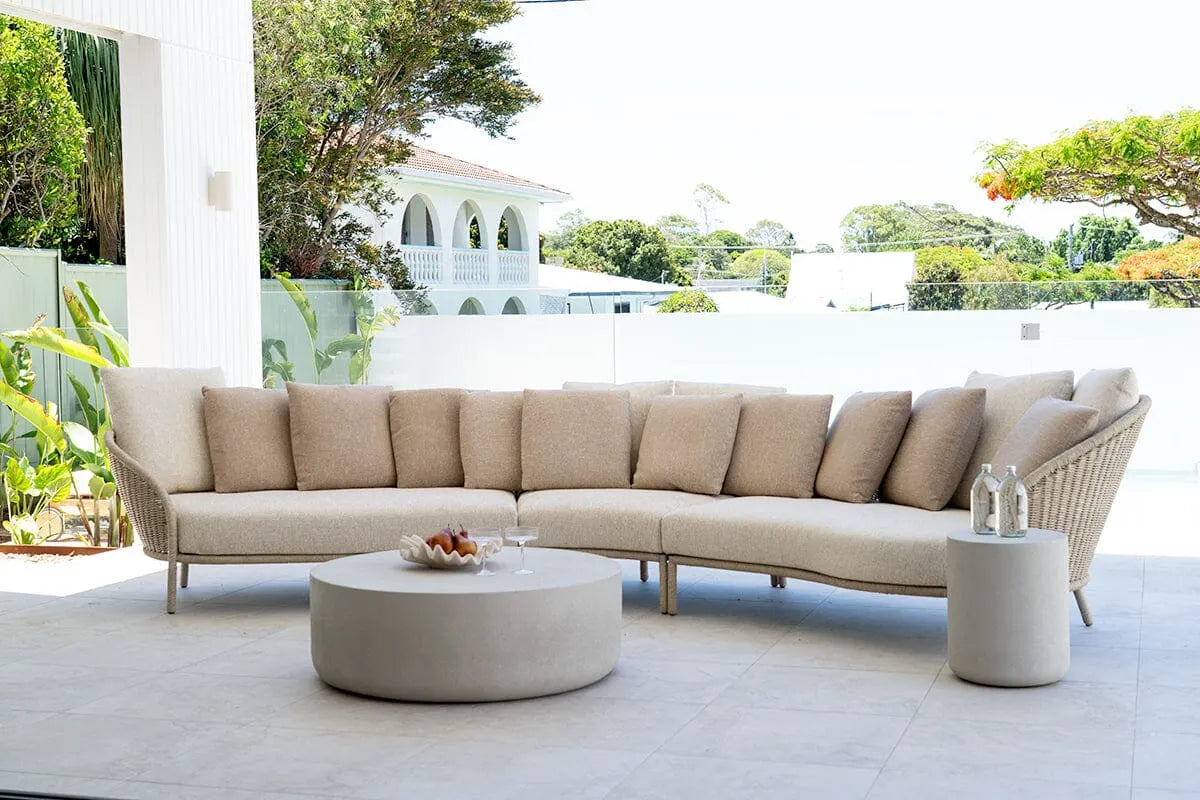 Beige outdoor sectional sofa with a round coffee table on a patio.