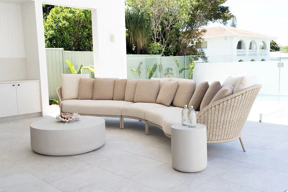 Modern outdoor patio set with a curved sectional sofa and round coffee table on a patio.
