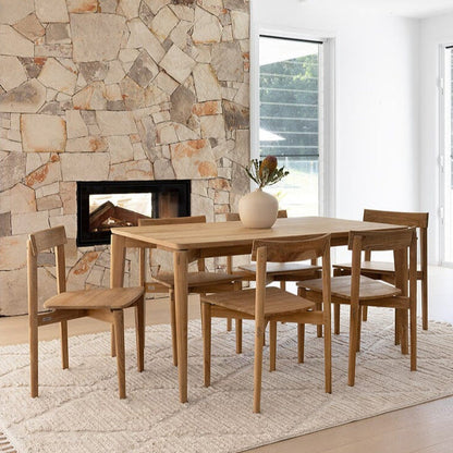 Dining room with wooden table and chairs against a stone wall.