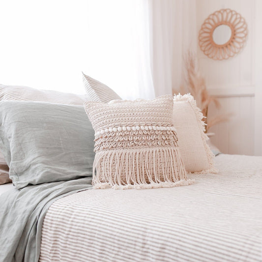 Neatly made bed with decorative pillows and a white headboard.