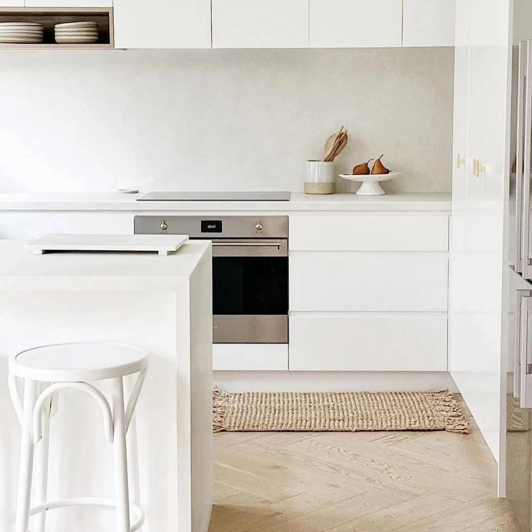 Modern kitchen with white cabinets, stainless steel appliances, and a light wood floor.