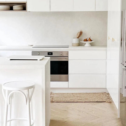 Modern kitchen with white cabinets, stainless steel appliances, and a light wood floor.