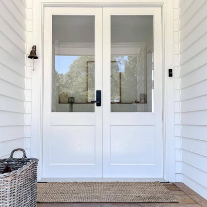 White double front door with glass panels, with natural jute door mat on a house exterior.