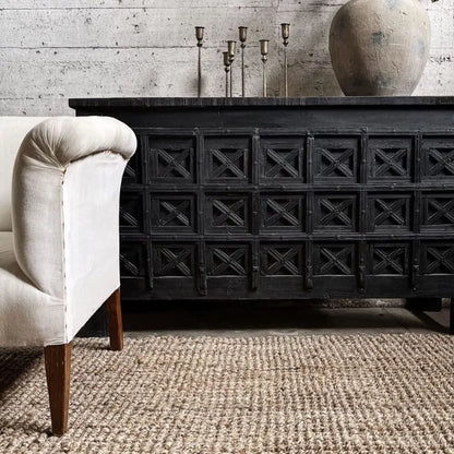 Black wooden sideboard with decorative elements in a room with a textured wall and jute rug