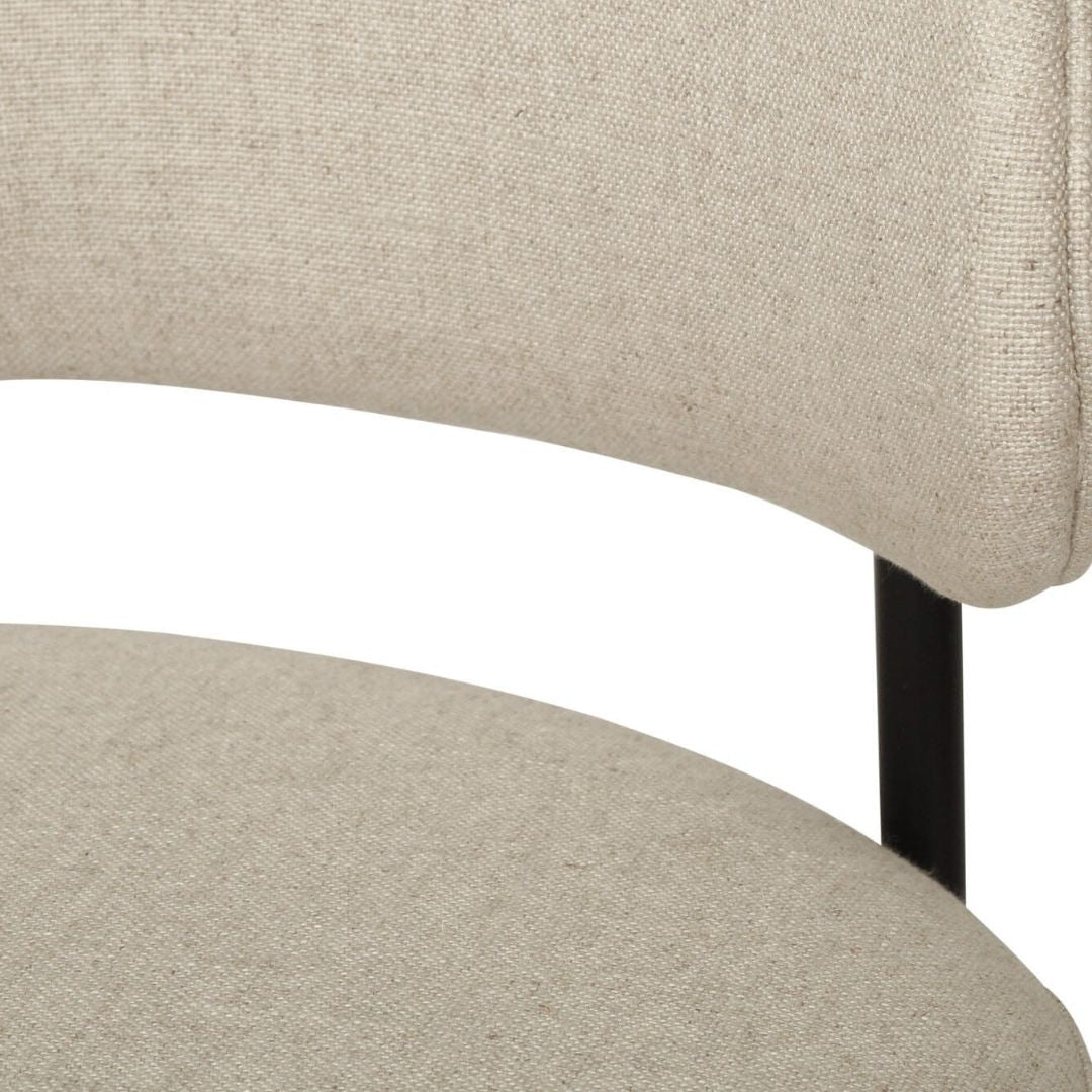 Close-up of a beige upholstered chair with a black metal leg on a white background