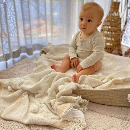 Baby sitting on a textured blanket in a softly lit room