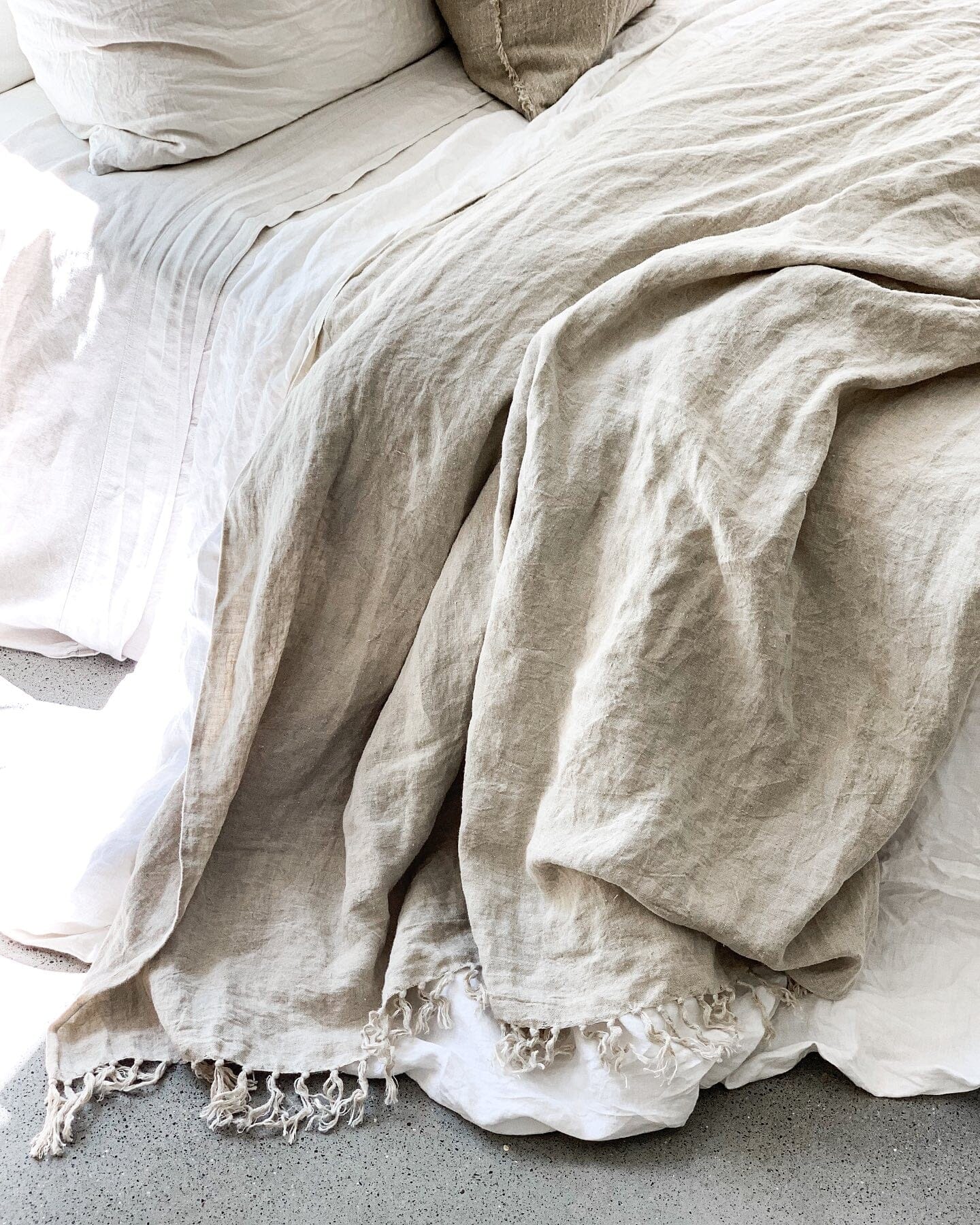 Close-up of beige textured blanket on a bed with white bedding