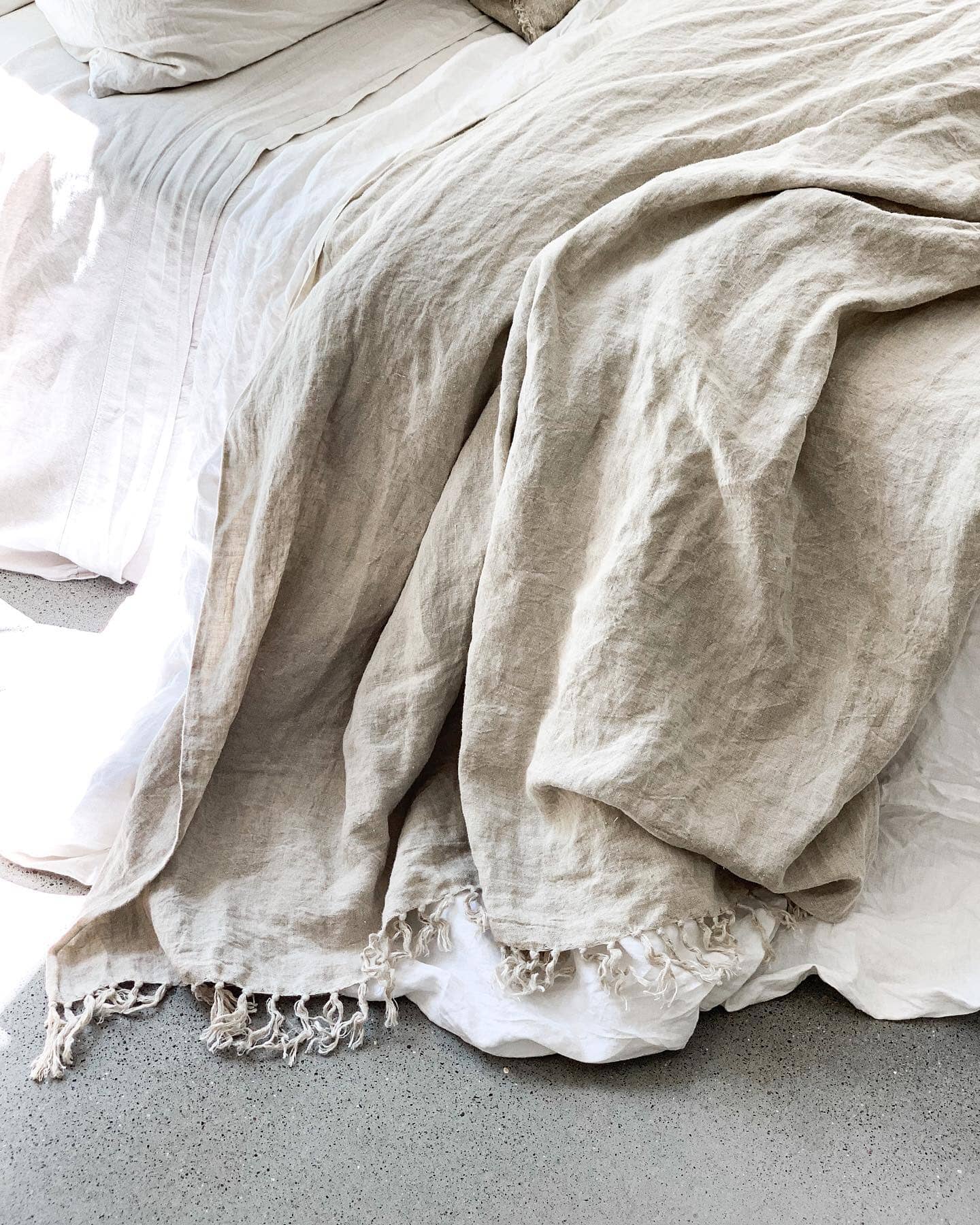 Close-up of textured beige blanket with tassels on a neutral background