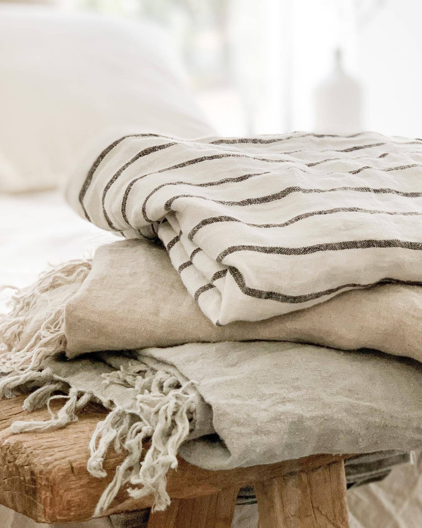 Stack of folded towels with striped pattern on a wooden stool