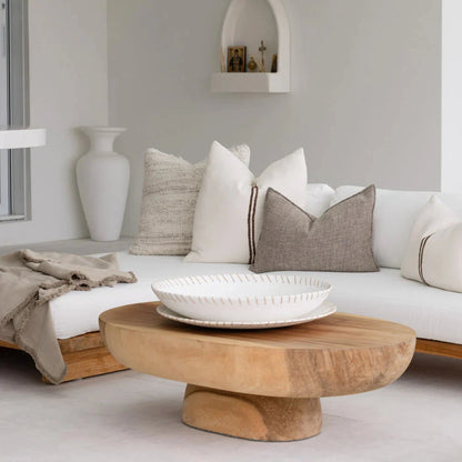 Modern living room with a wooden coffee table, white sofa, and decorative pillows.