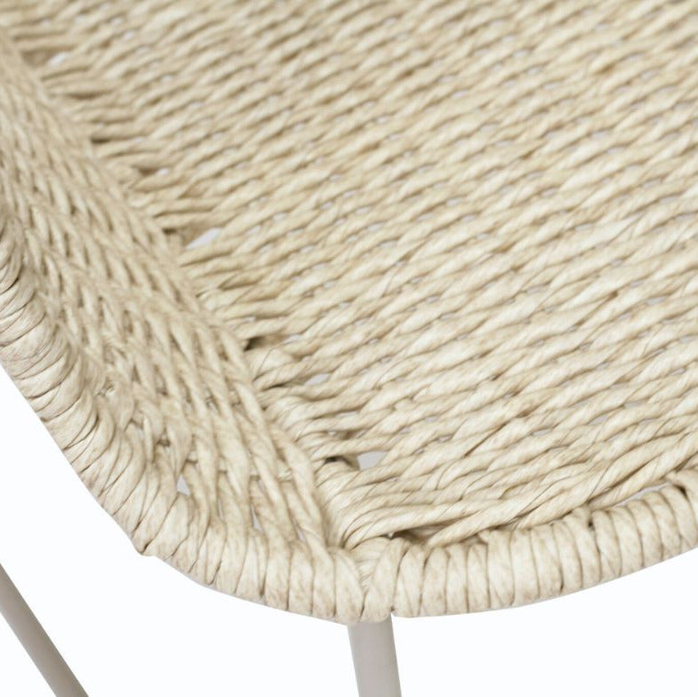 Close-up detail of a woven natural-fiber chair seat showing the texture and cream-colored rope material, with a small portion of a light-colored metal leg visible against a white background.