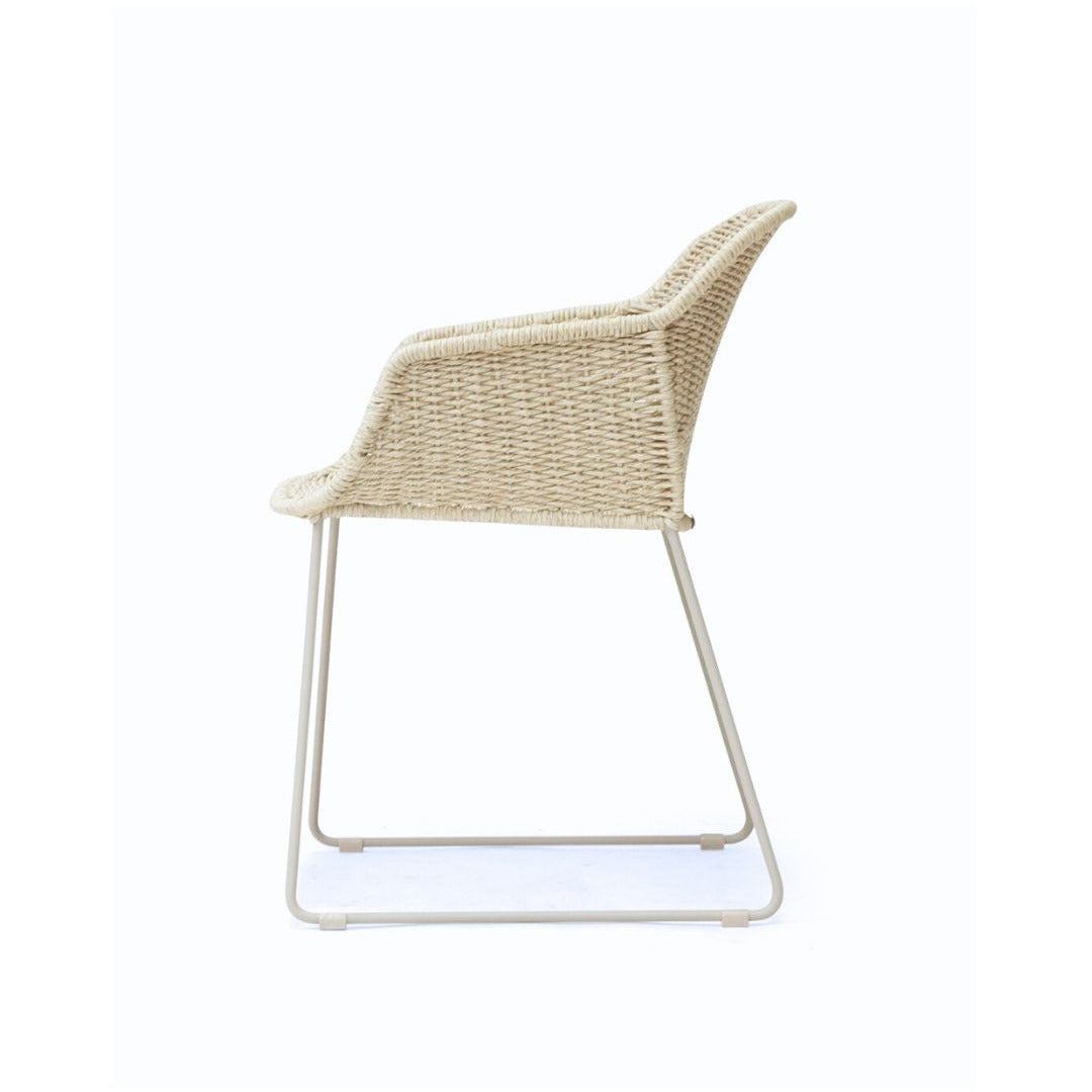 A modern outdoor armchair with a woven beige wicker seat and backrest, supported by a slim white metal frame, shown from a side profile on a white background.