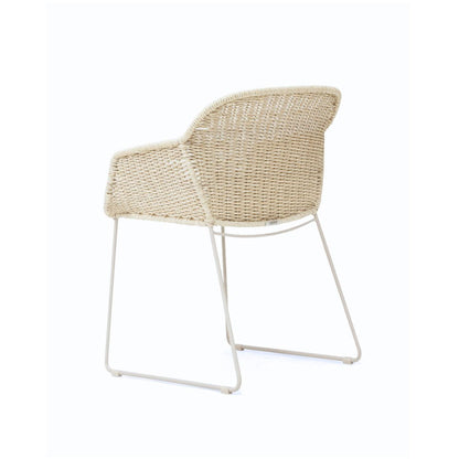 A modern outdoor armchair with a woven beige wicker seat and backrest, supported by a slim white metal frame, shown against a plain white background.