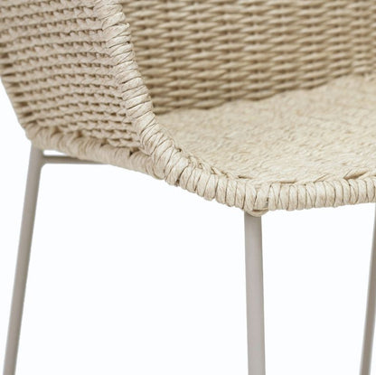 Close-up of a woven chair seat and back in a natural beige tone with thin white metal legs, shown against a plain white background.