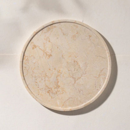 Round beige marble tray on a light beige background