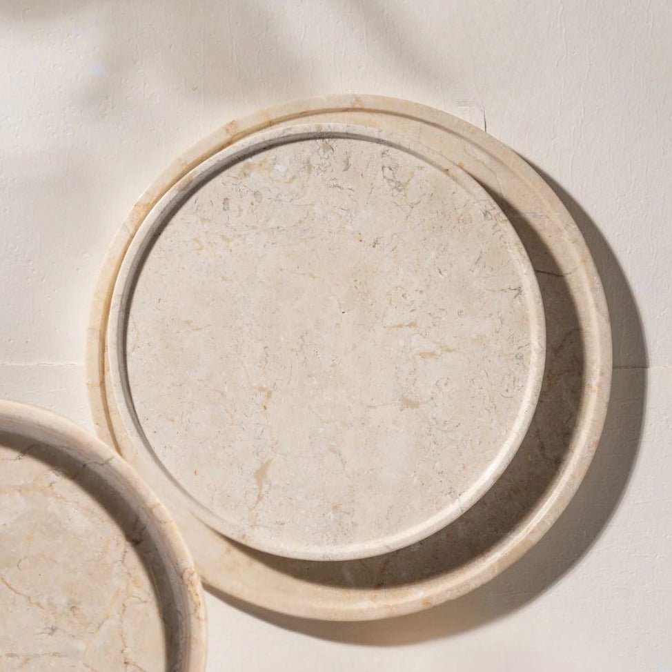 Round stone tray with a natural beige color on a light beige background