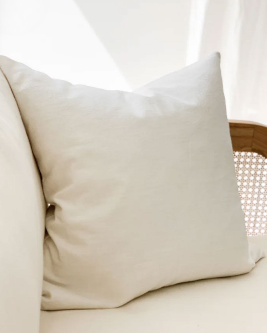Beige pillow on a beige sofa with a blurred white background