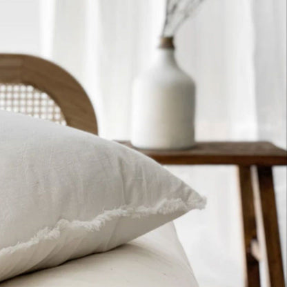 Chalk white ramie cushion cover with hand-finished fringe edges on modern neutral sofa