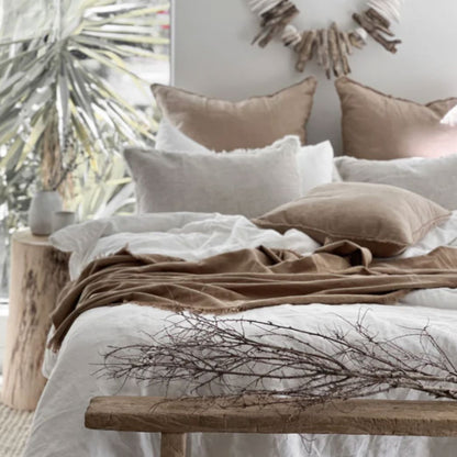Cozy bedroom with neutral tones, pillows, and a wooden bench.