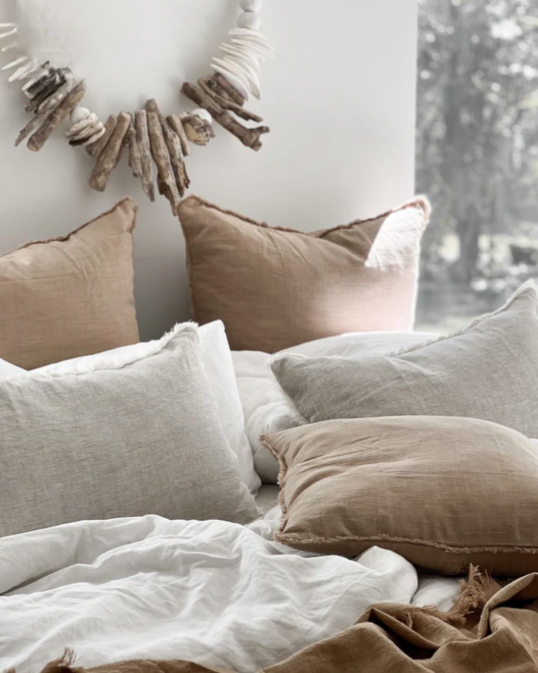 Cozy bedroom with neutral-colored pillows and a decorative wall piece.