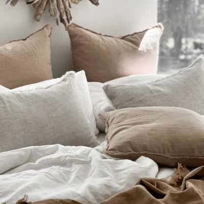 Cozy bedroom with neutral-colored pillows and a decorative wall piece.