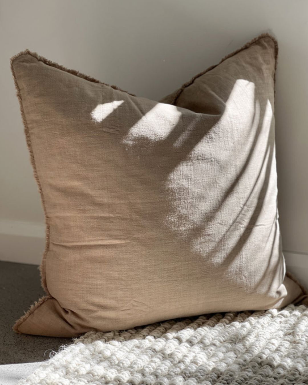 Beige pillow on a textured surface with a neutral background