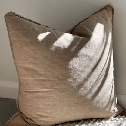 Beige pillow on a textured surface with a neutral background