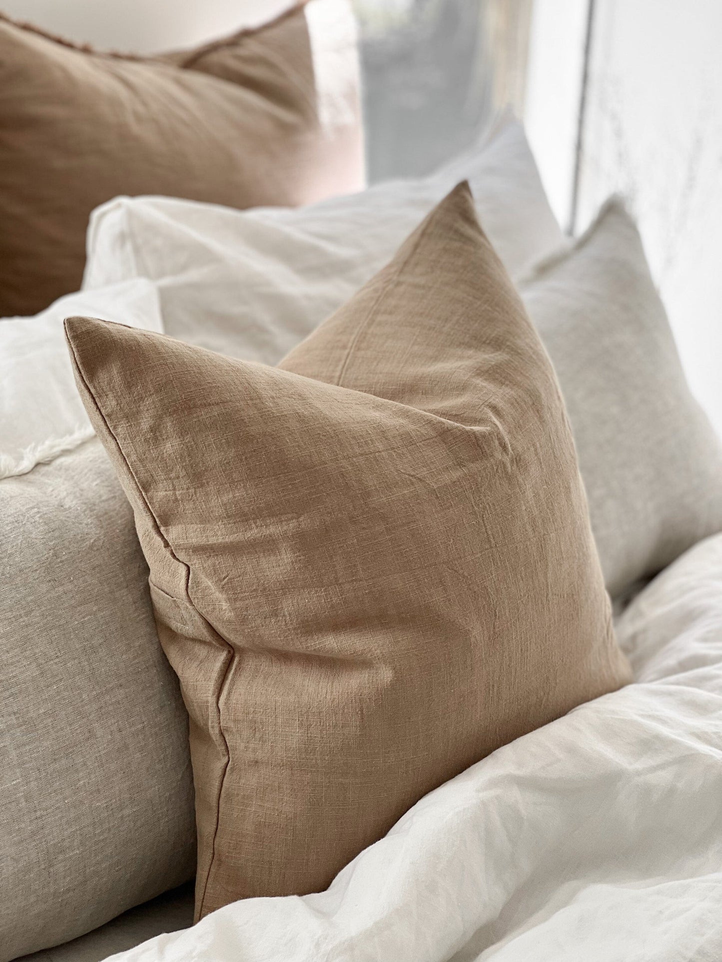 Beige pillow on a bed with white bedding