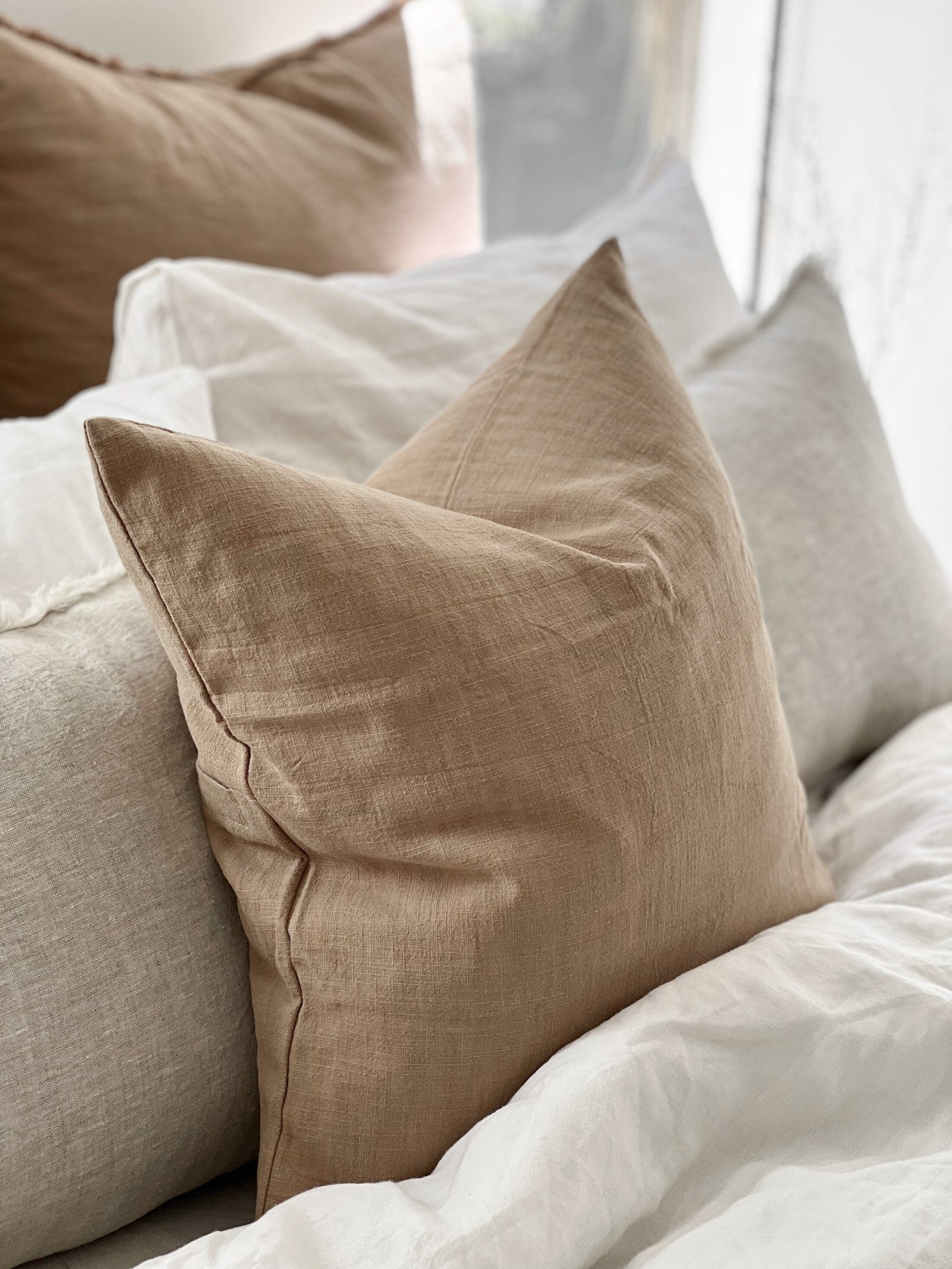 Beige pillow on a bed with white bedding