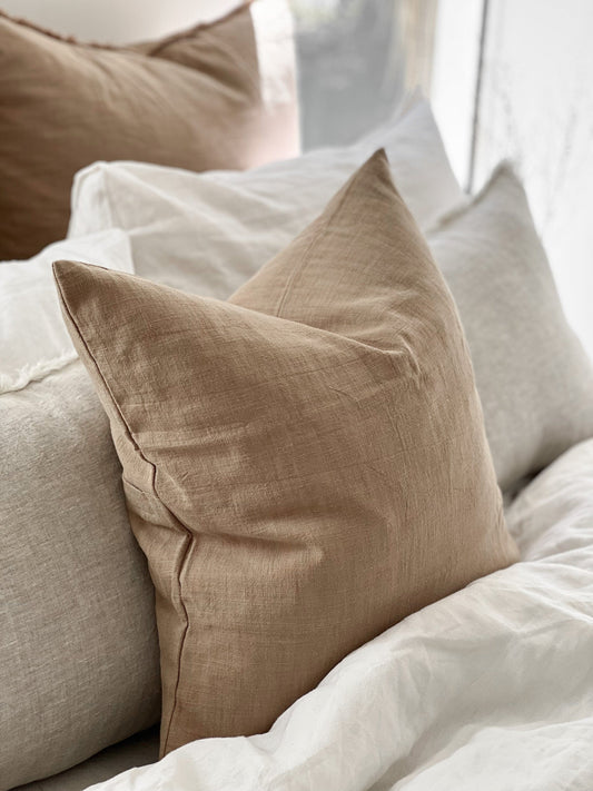 Beige pillow on a bed with white bedding