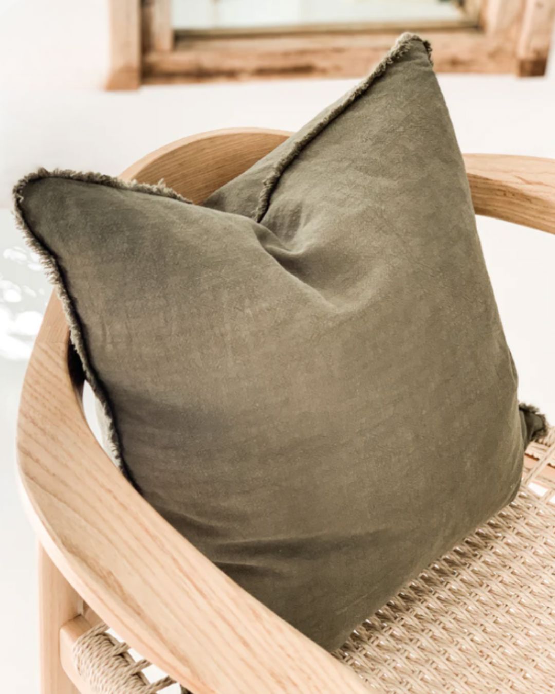 Olive Green pillow on a wooden chair with a blurred background