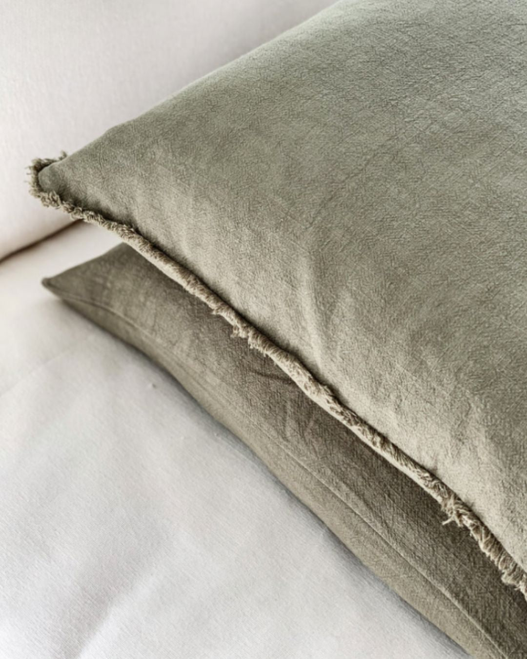 Two green pillows on a white surface